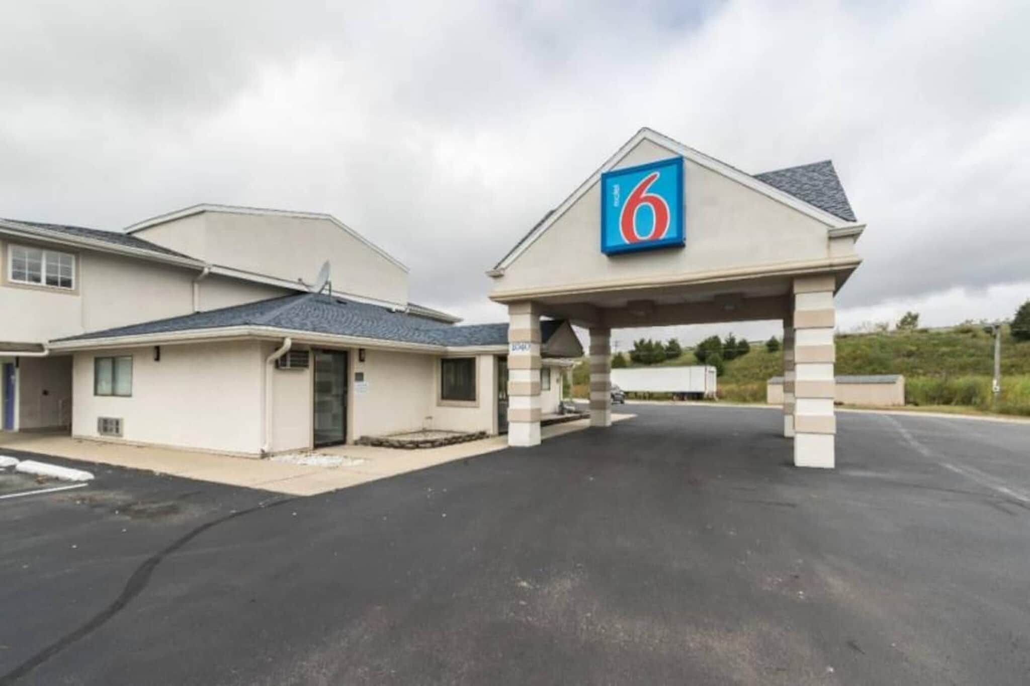A motel with a prominent '6' sign, a covered parking area, and a building with a sloped roof.