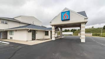 A motel with a prominent '6' sign, a covered parking area, and a building with a sloped roof.