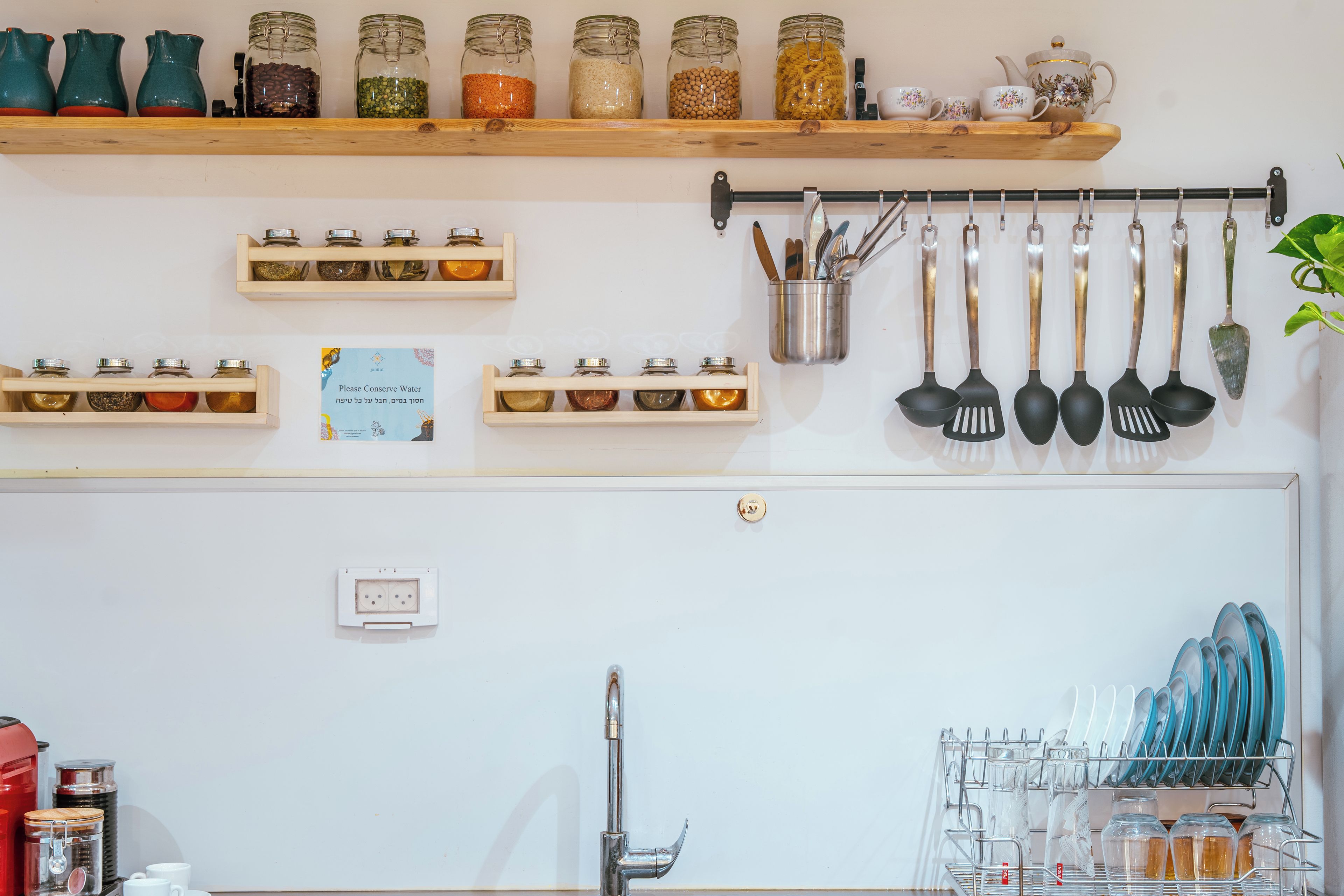 A kitchen with shelves holding jars of spices, a tea set, and utensils.
