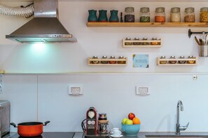 A kitchen with a stove, a sink, and various jars on shelves.