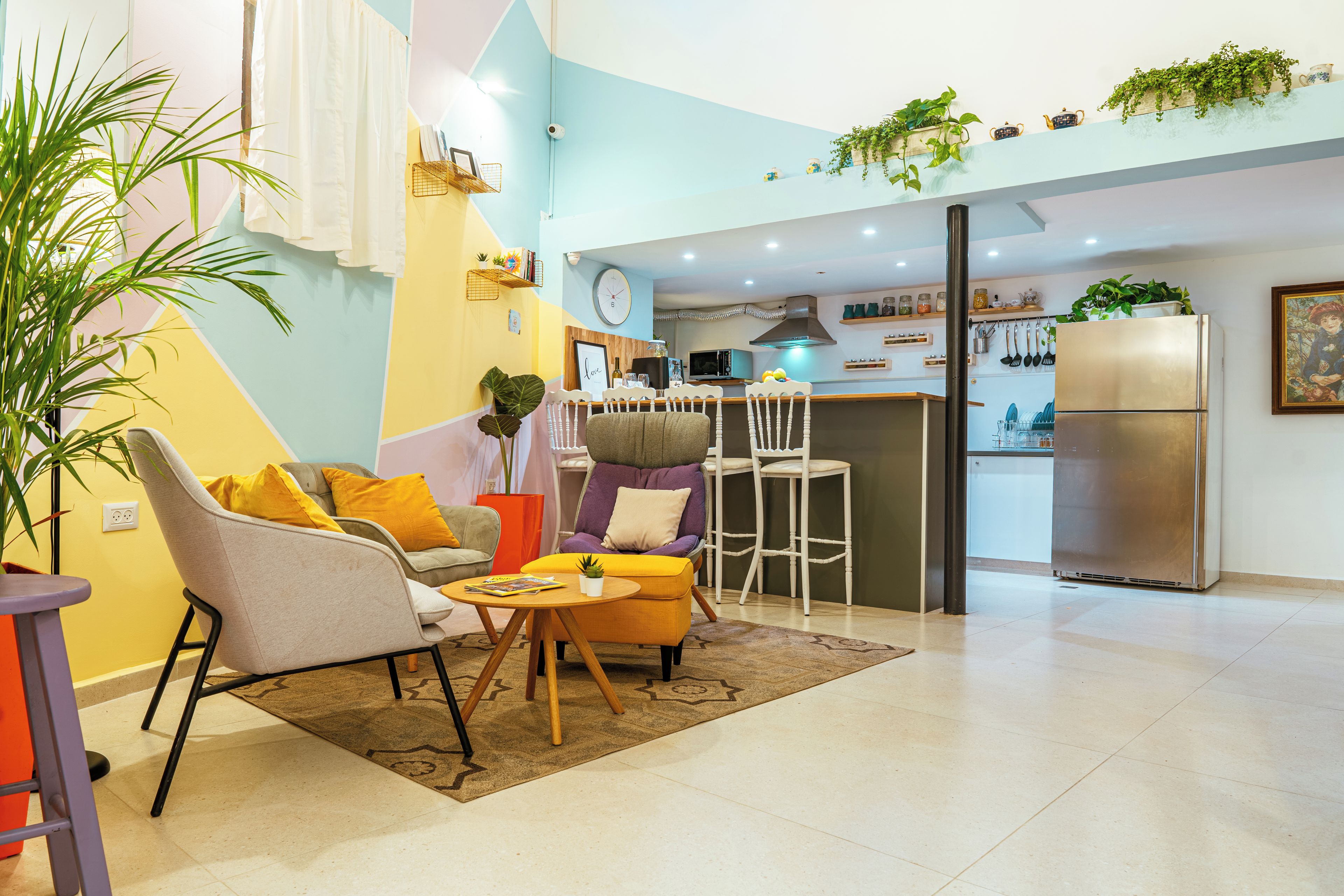 Un salon moderne avec un canapé, des fauteuils et une table basse. Il y a également un coin cuisine équipé d’un réfrigérateur et d’un four à micro-ondes.