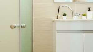 Un baño con un lavamanos blanco, un espejo y una puerta.