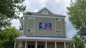 Een gebouw met twee verdiepingen, met een bord waarop staat dat het een 6th Studio motel is, nu geopend.