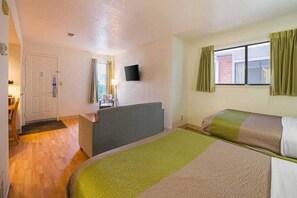 A hotel room with two beds, a desk, a chair, a television, and a window with curtains. - 2 Full Beds | Smoking (Greensboro)