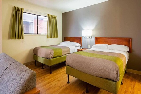 A hotel room with two single beds, a wooden floor, a window with curtains, and a chair. - 2 Full Beds | Smoking (Greensboro)