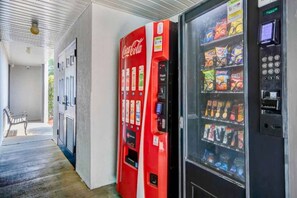 Un espace comprenant des distributeurs automatiques, notamment un distributeur de boissons Coca-Cola et un autre distributeur de boissons.