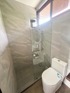 Ein Badezimmer mit einer Duschkabine, einer weißen Toilette und einem gefliesten Boden.