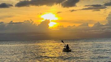 A kayaker on a calm body of water during sunset.