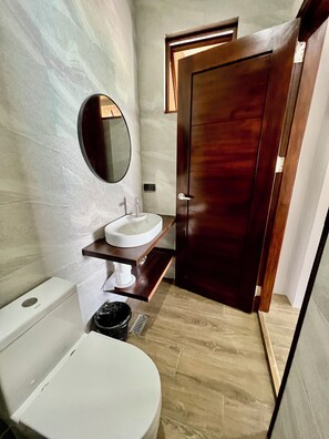Ein Badezimmer mit Toilette, Waschbecken, Spiegel und einer Holztür.