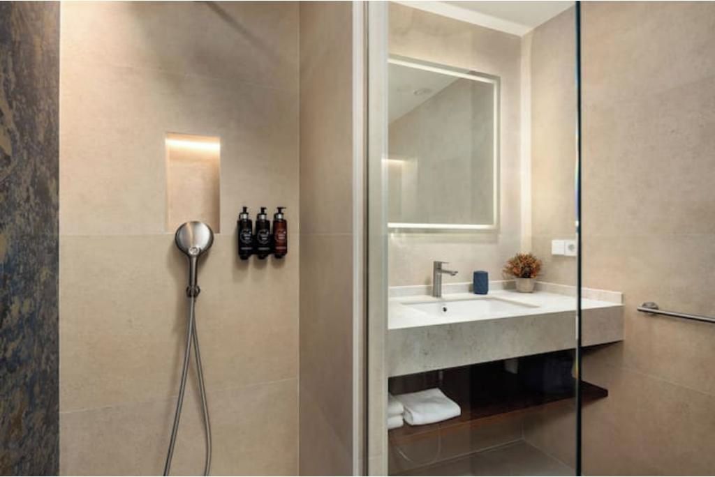 Ein modernes Badezimmer mit einer Duschkabine aus Glas, einem integrierten Waschbecken und einem Spiegel über dem Waschtisch.