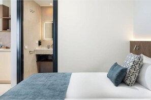 A hotel room with a bed, a bedside table, a nightstand, a mirror, and a bathroom visible through an open door. - "Indigo" Apartment (Estepona)
