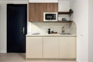A modern kitchen with a microwave, sink, and wooden cabinets. - "Indigo" Apartment (Estepona)