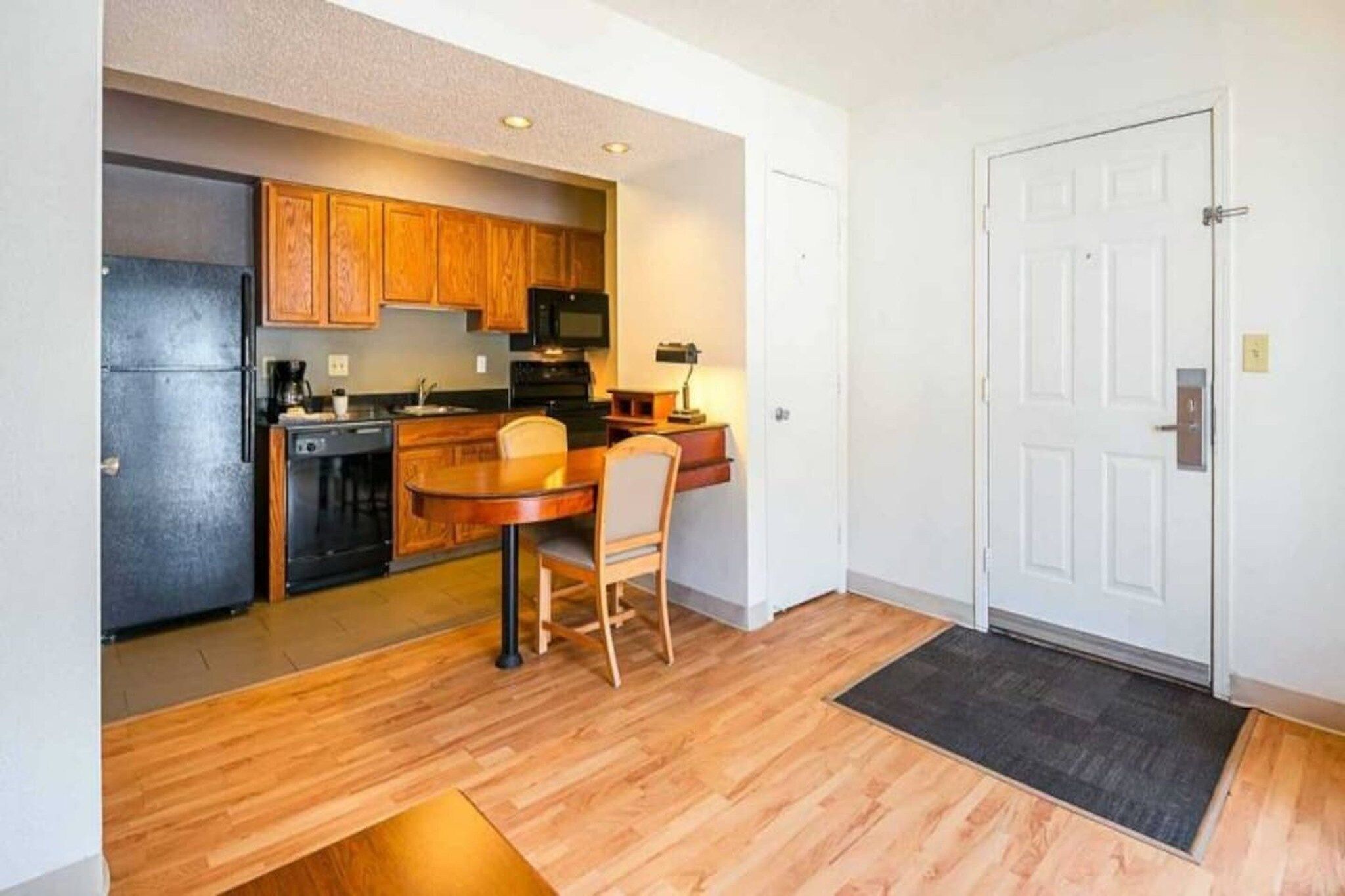 Una cocina compacta con muebles de madera, un refrigerador y un microondas.