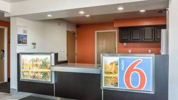 A reception area with a counter, a sign indicating a motel number, and a poster with a message.
