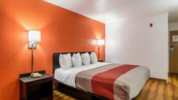 A hotel room with a bed, nightstands, and a red and white striped blanket.
