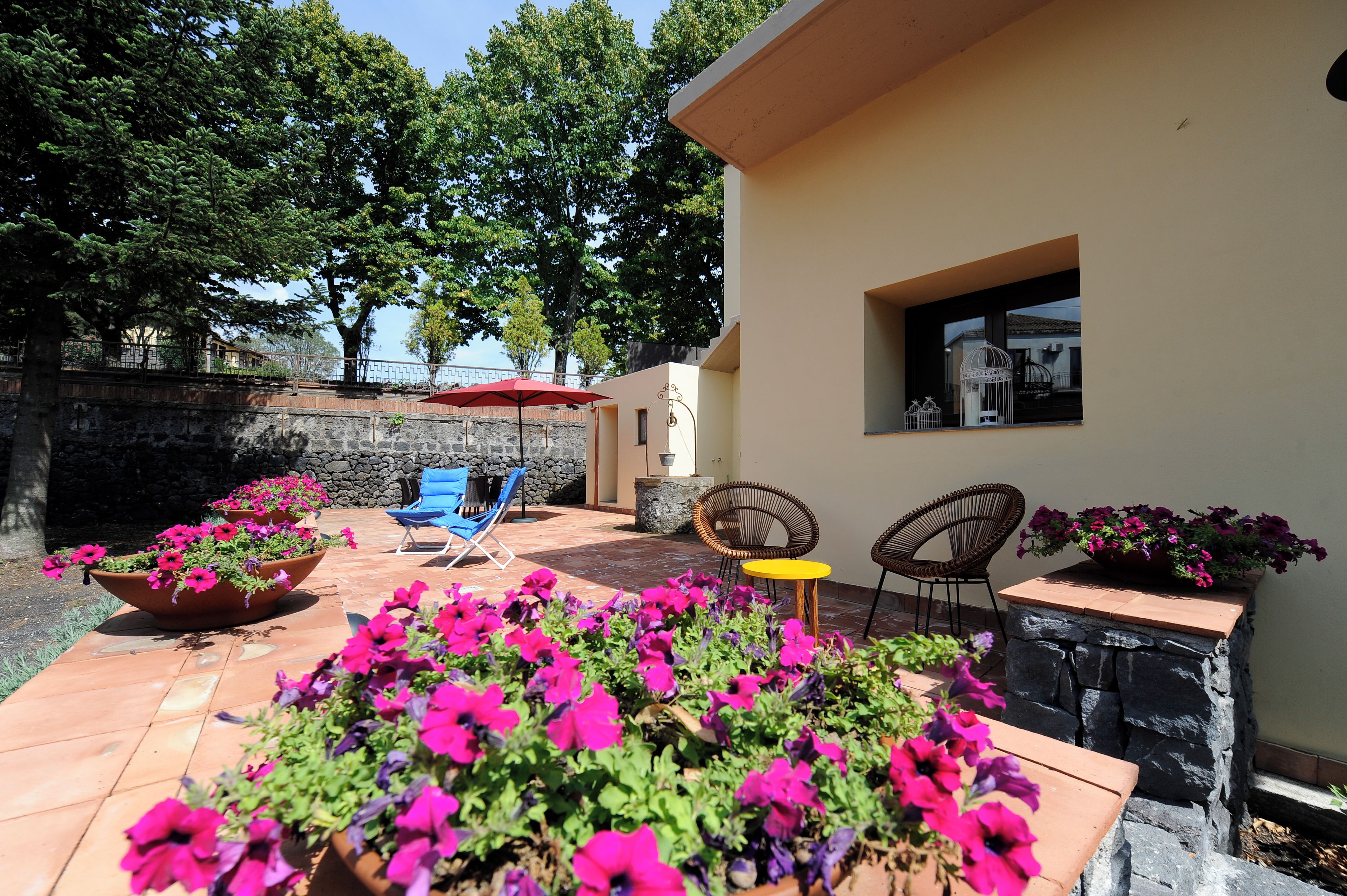 A patio area with outdoor seating, a stone wall, and potted plants.