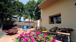 A patio area with outdoor seating, a stone wall, and potted plants. - Vrbo Property (Fornazzo)