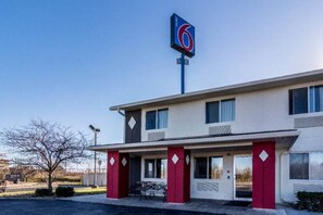 A motel with a prominent '6' sign, a flat roof, and a simple facade with a red door and windows. - 2 Queen Beds | Smoking (HARRISVILLE)