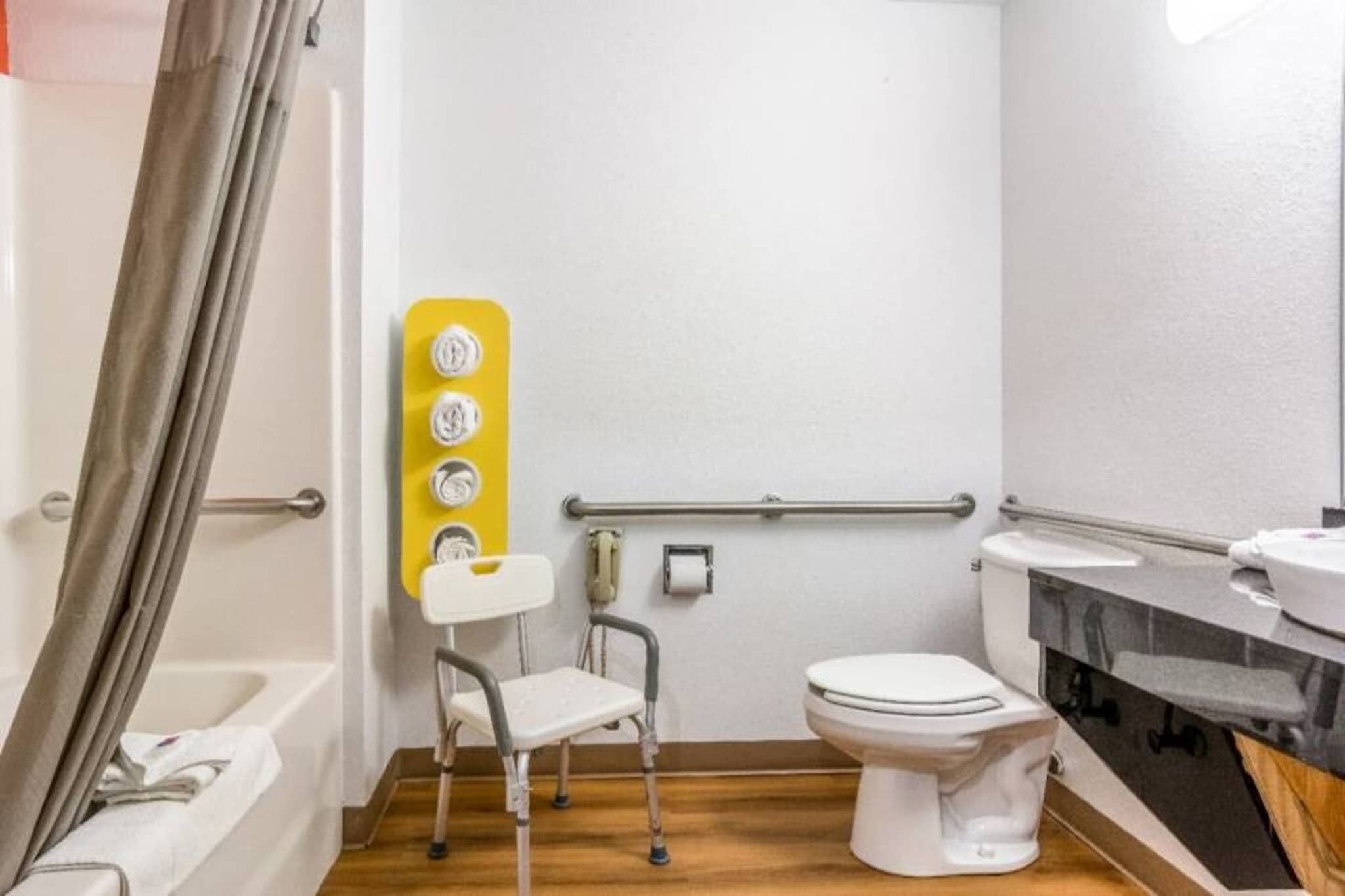 A bathroom with a wheelchair-accessible shower area, a toilet, and a sink.