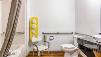 A bathroom with a wheelchair-accessible shower area, a toilet, and a sink.