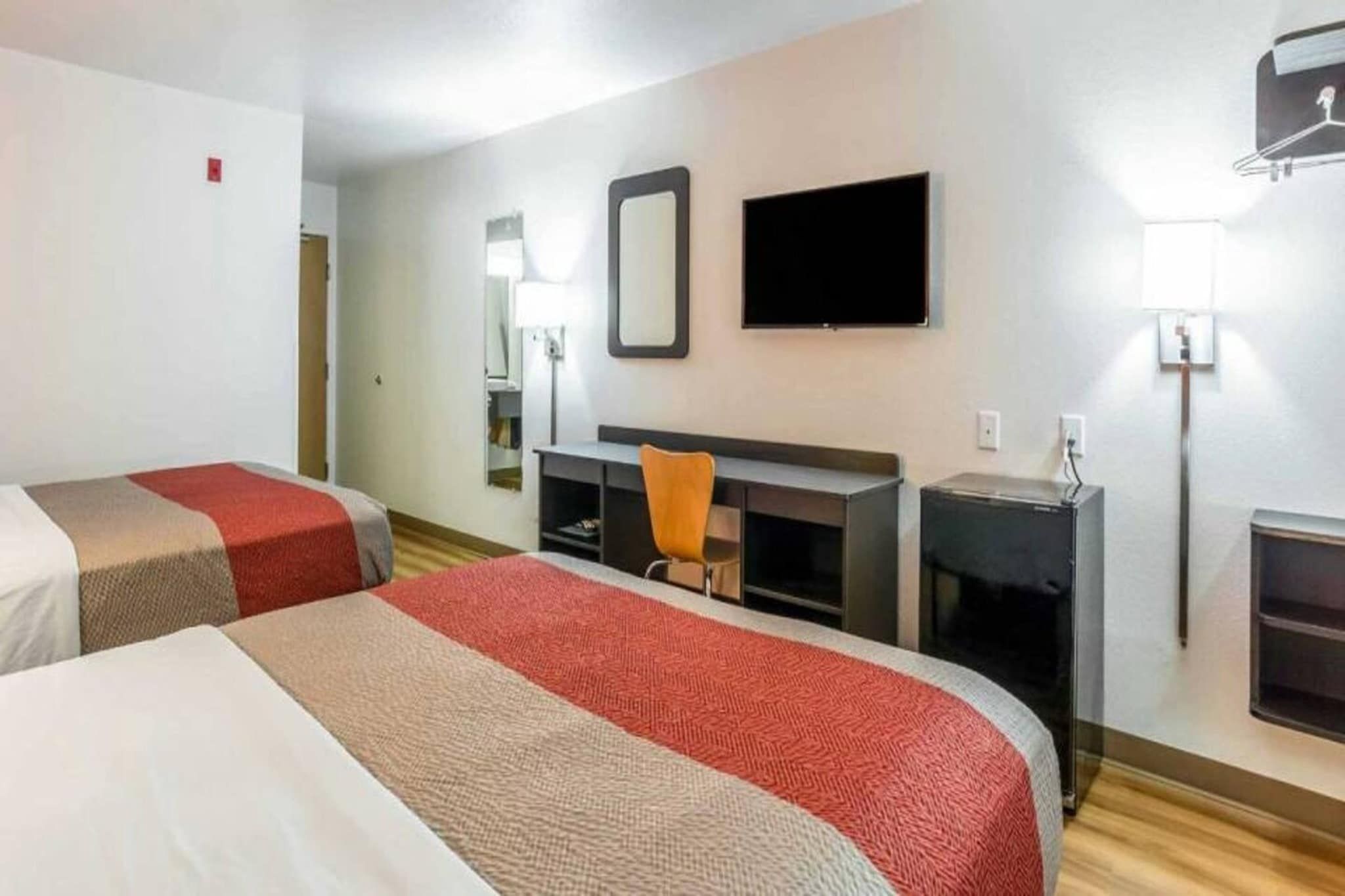 Habitación de hotel con dos camas, un escritorio, una silla, un televisor y una chimenea.