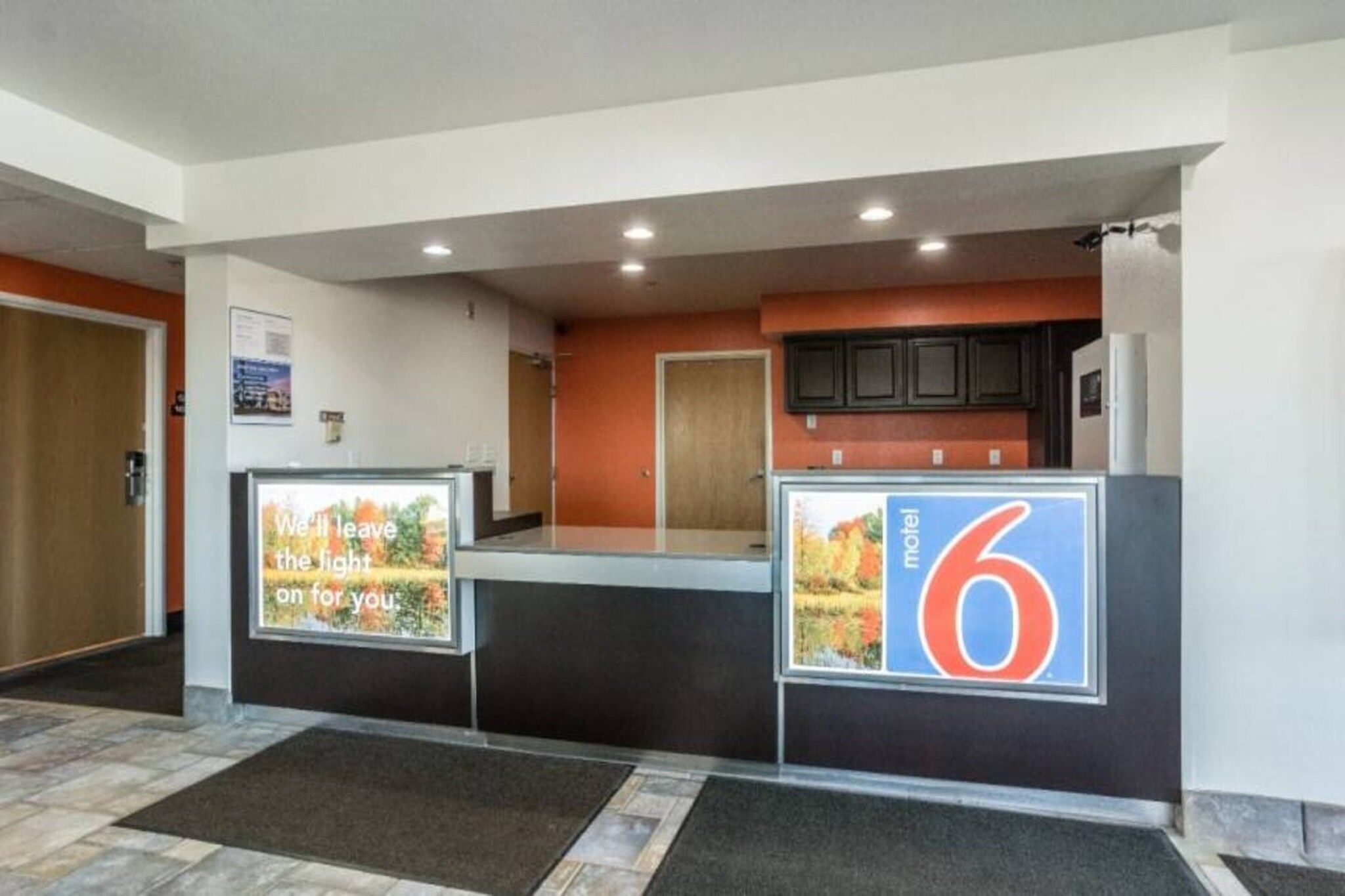 A hotel reception area with a counter, a refrigerator, and a sign indicating room number 6.