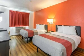 A hotel room with two beds, a desk, and a window with red curtains. - 2 Queen Beds | Smoking (HARRISVILLE)