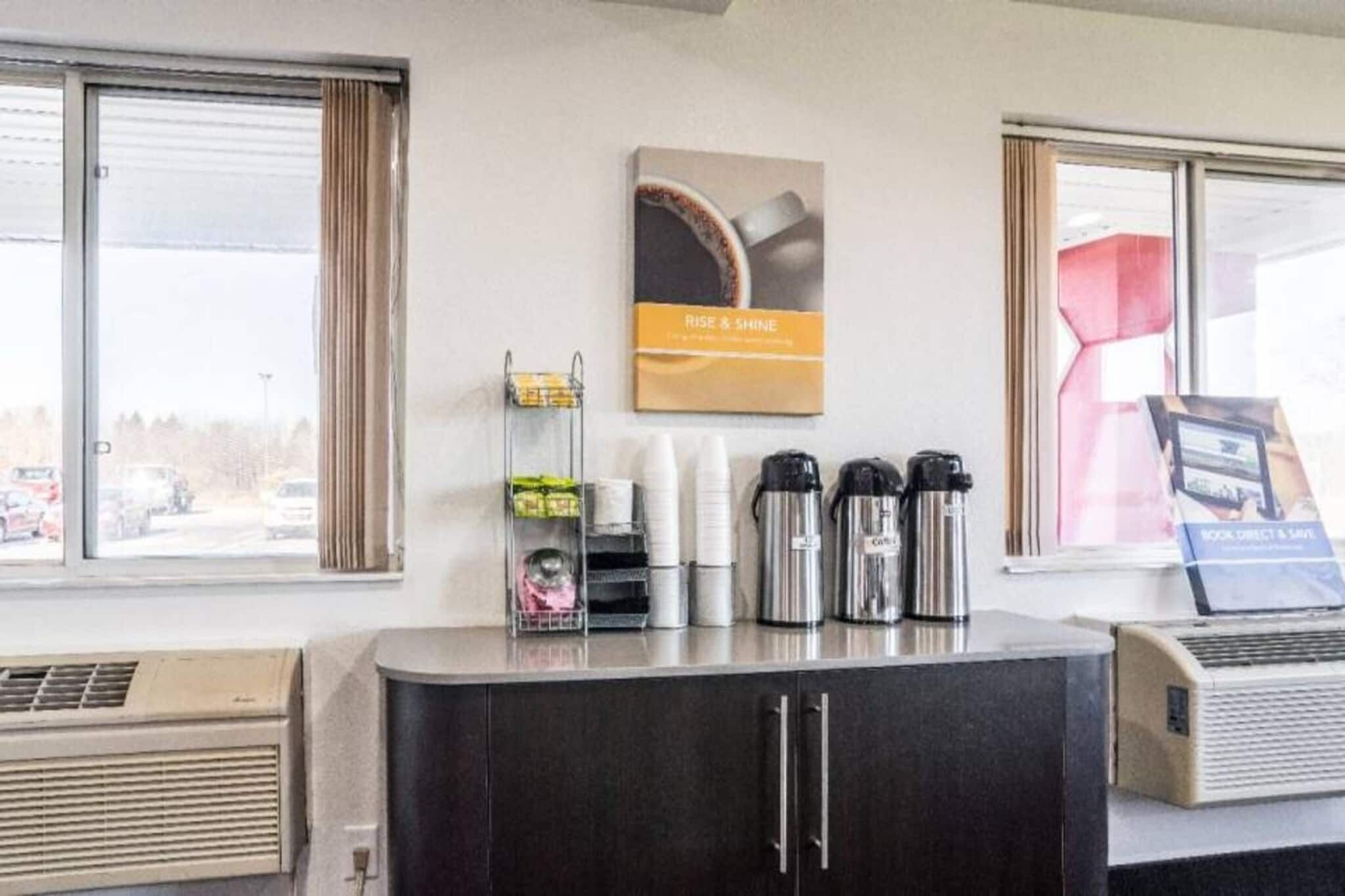 A hotel reception area with a counter, coffee makers, and a poster on the wall.