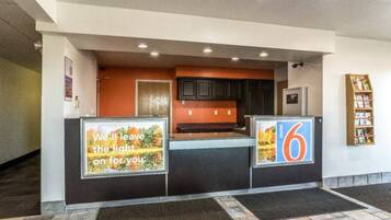 A reception area with a counter, a sign with the number 6, and a poster with a message.