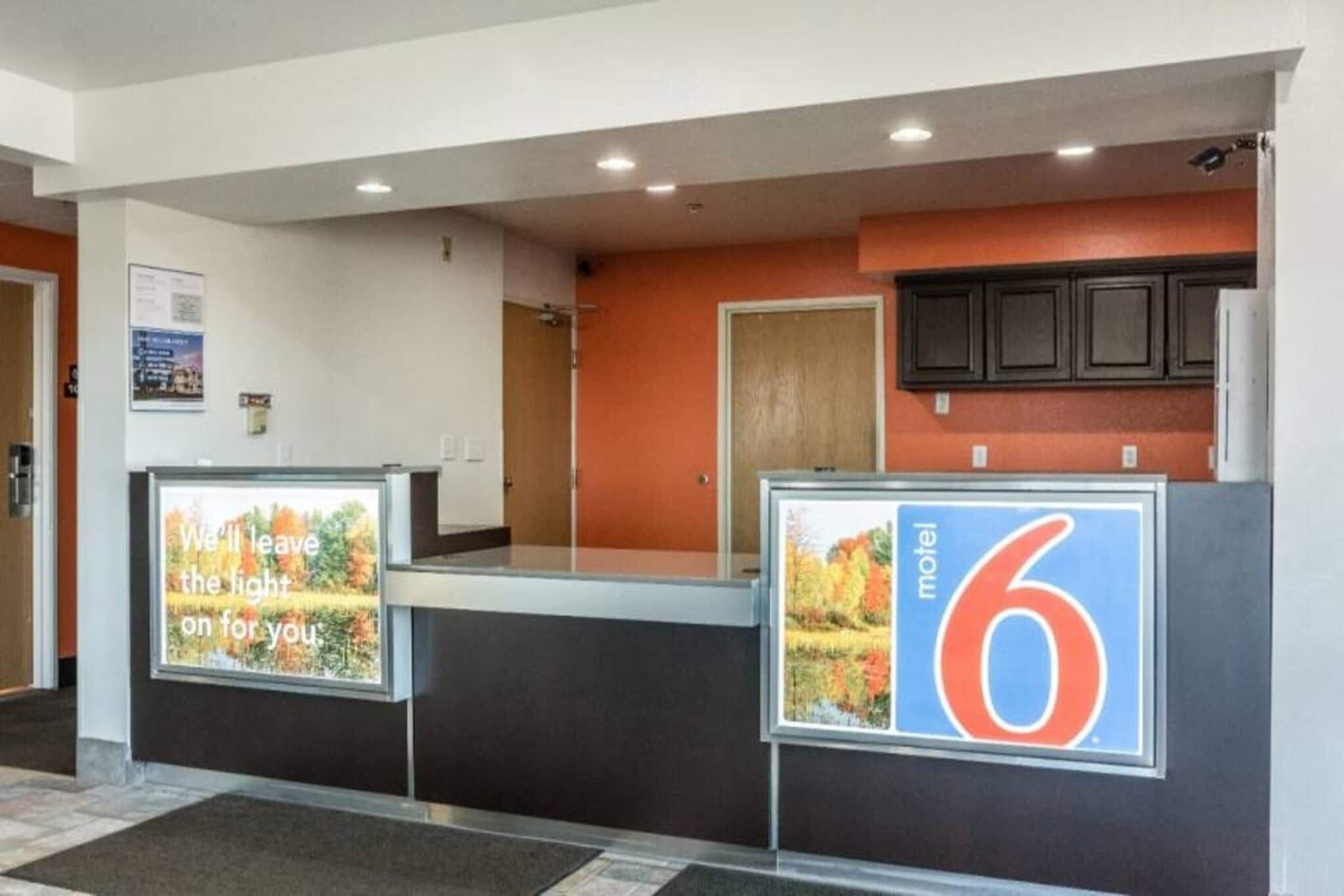 A reception area with a counter, a sign indicating a motel number, and a poster with a message.