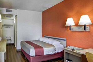 A hotel room with a bed, bedside table, lamp, and a phone. - 1 Queen Bed | Micfridge (Medford OR)