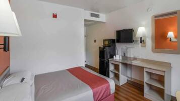 A hotel room with a bed, a desk, a television, and a kitchenette.