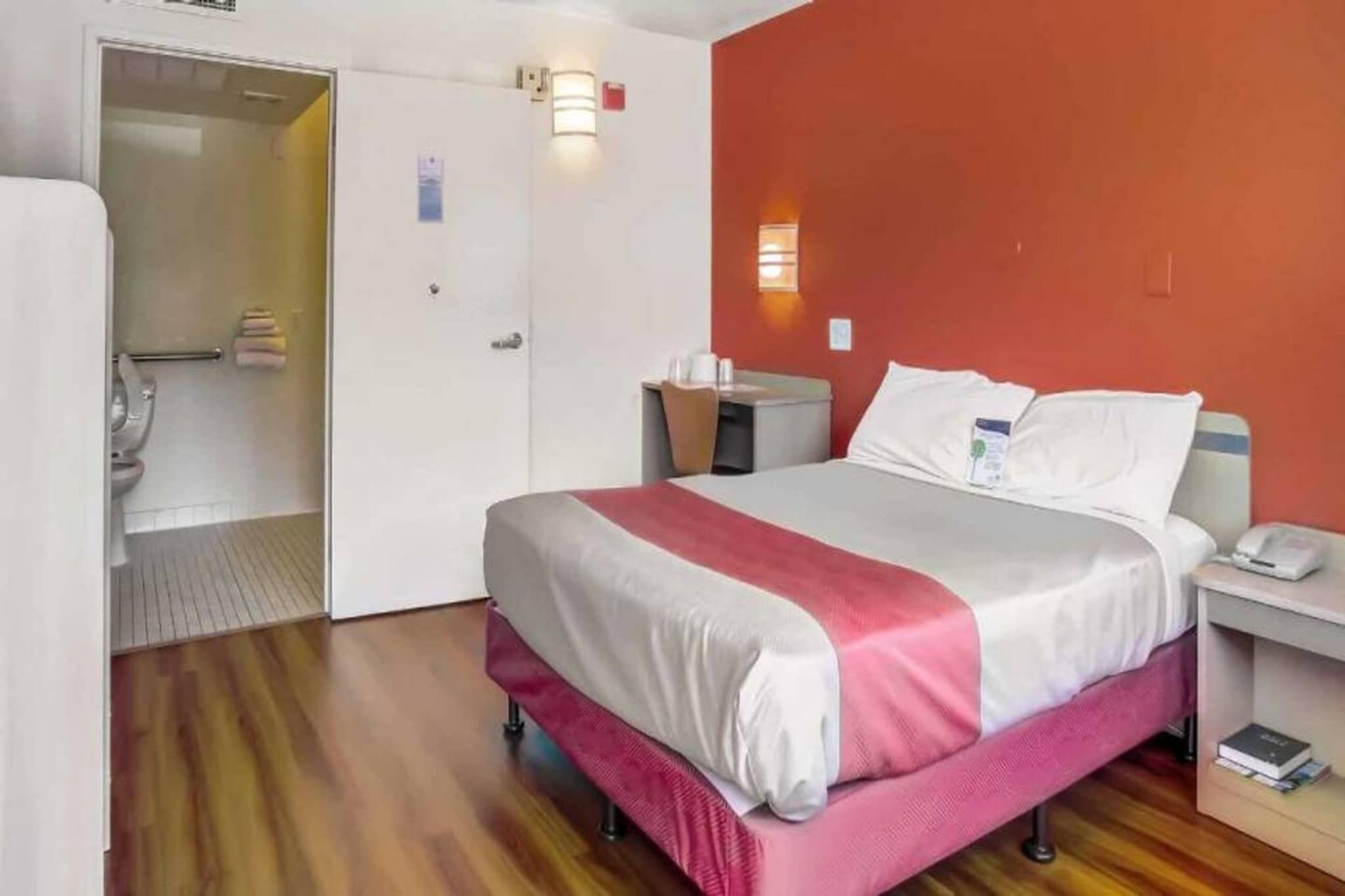 Ein Hotelzimmer mit Bett, Nachttisch und einer Badezimmertür.
