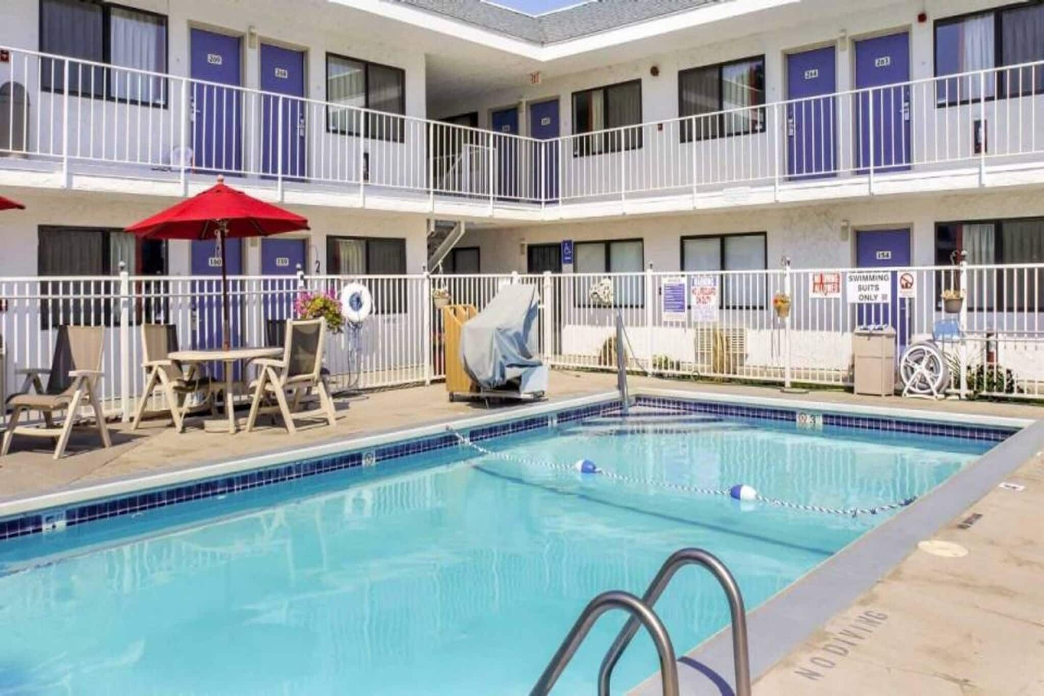 Ein Hotel mit Pool, Sitzgelegenheiten im Freien und einem überdachten Bereich.