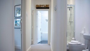 A hallway leading to a bathroom with a toilet, shower, and a sign above the door. - Malvern Hills 3-Bed Retreat | Sleeps 8 | Free Park (Worcestershire)