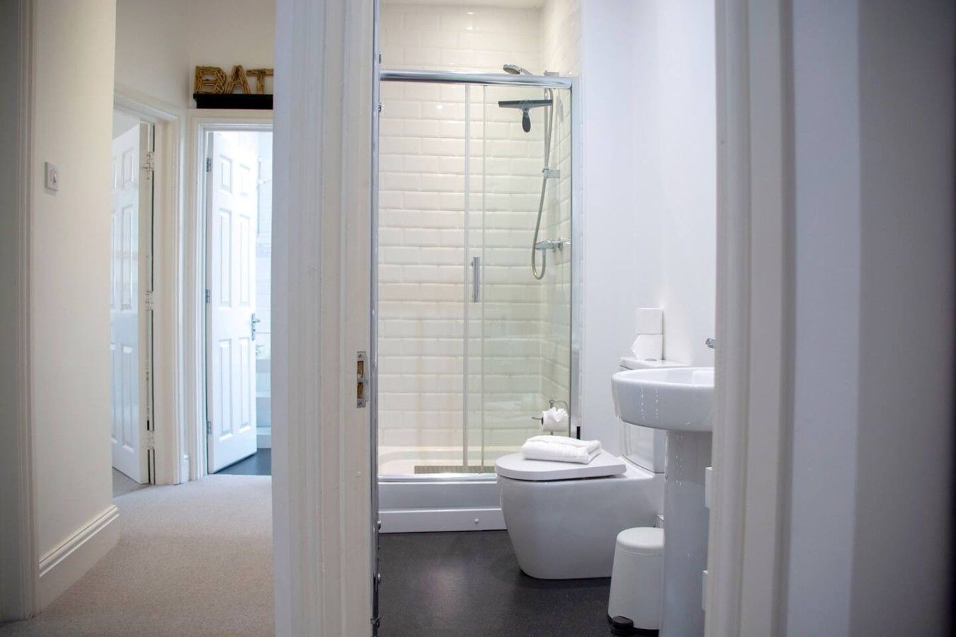 Une salle de bain moderne avec une douche à parois de verre, des toilettes blanches et un lavabo.