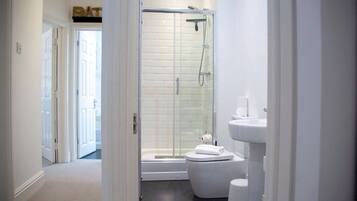 Une salle de bain moderne avec une douche à parois de verre, des toilettes blanches et un lavabo.