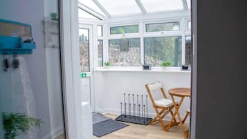 Une véranda avec une chaise et une table en bois, un radiateur et une vue sur l’extérieur.