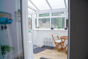 Un conservatorio con una silla y una mesa de madera, un radiador y vistas al exterior.