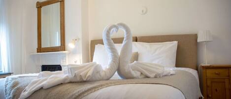A hotel room with a bed, a wooden nightstand, a mirror, and a lamp.