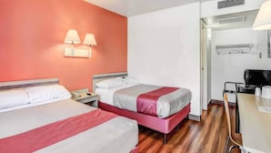 Et hotelværelse med to senge, et skrivebord og et tekøkken.