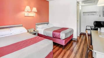 Ein Hotelzimmer mit zwei Betten, einem Schreibtisch und einer Küchenzeile.