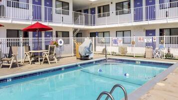 Ein Hotel mit Pool, Sitzgelegenheiten im Freien und einem überdachten Bereich.