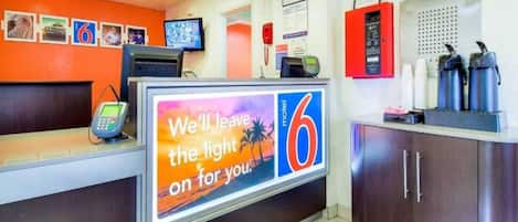 A hotel reception area with a digital display, a phone, and a counter.