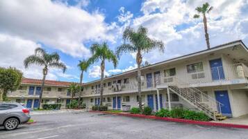 A motel with multiple-story buildings, a parking lot, and palm trees.