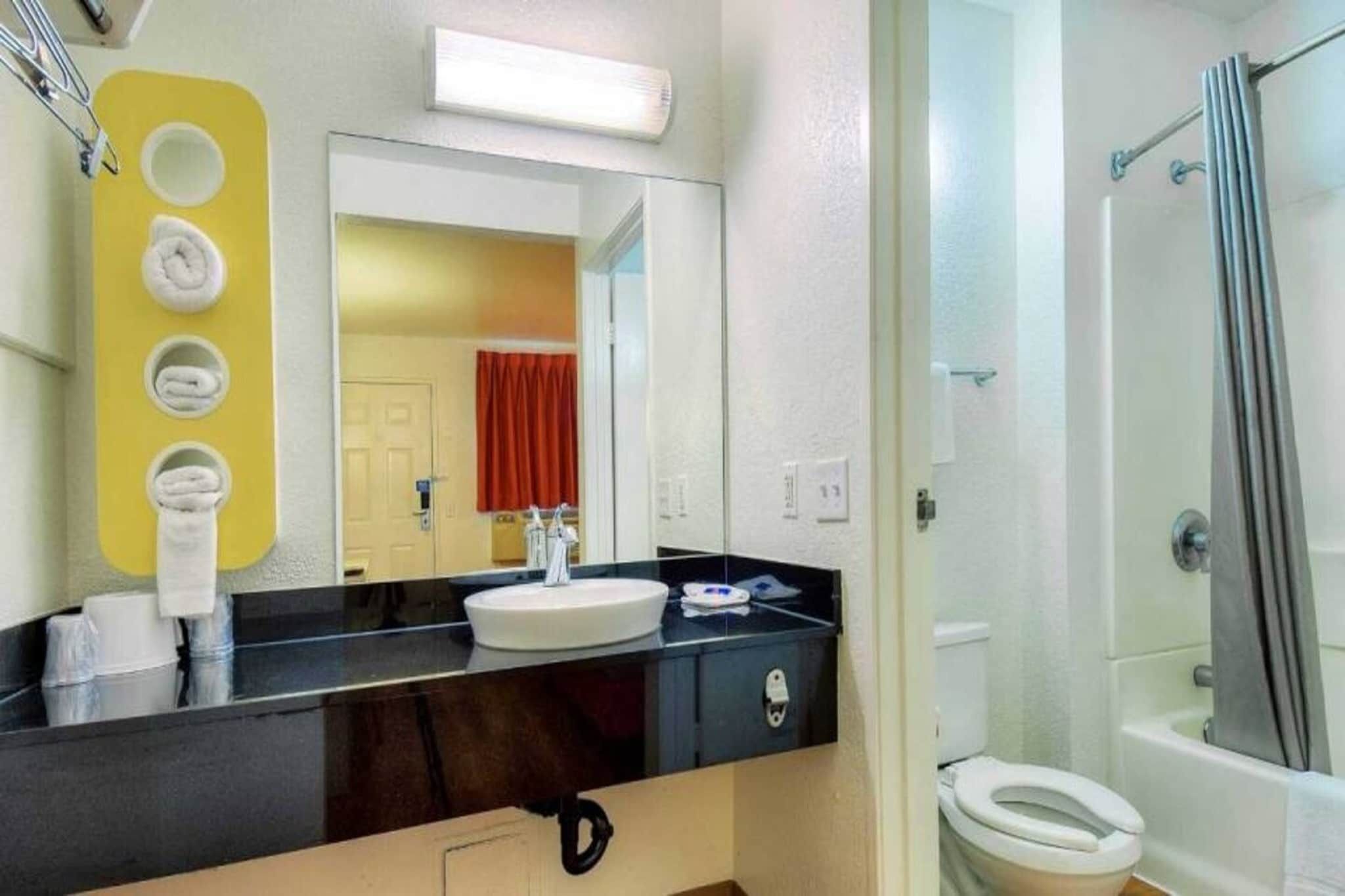Ein Badezimmer mit schwarzem Waschtisch, weißem Waschbecken und einer Duschkabine.