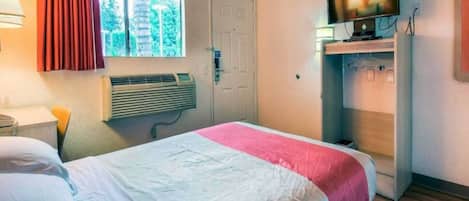 Une chambre d’hôtel avec un lit, une télévision, un radiateur et une fenêtre avec des rideaux.