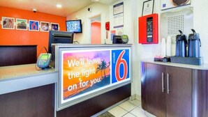 A hotel reception area with a digital display, a phone, and a counter. - 1 QUEEN BED | DELUXE (Chino)