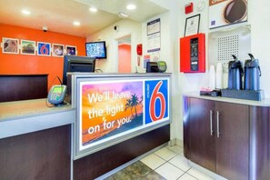 Un espace d’accueil d’hôtel comprenant un écran numérique, un téléphone et un comptoir.