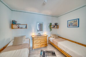 A bedroom with two single beds, a wooden dresser, a mirror, and a framed picture on the wall. - Vrbo Property (Heiligenhafen)
